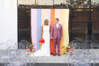 05 The wedding ceremony space was done with a bright striped backdrop, bright florals and sheer chairs