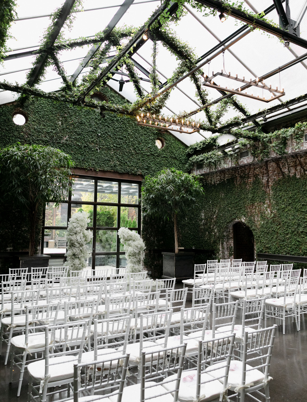 The wedding ceremony space was done with lots of greenery, chandeliers, a baby's breath altar and white chairs