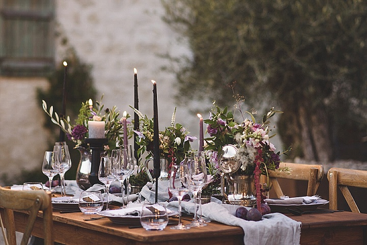 The wedding tablescape was done with a lilac table runner, purple and pink blooms, greenery, lilac and black candles and fruits