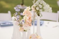 a French country cluster wedding centerpiece of white vases and mugs, pastel and white blooms and a table number