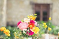 a bright cluster wedding centerpiece of hot pink and pink blooms plus yellow ones, billy balls and greenery for a bright summer wedding