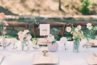a cluster wedding centerpiece of bud vases, with pastel and white blooms and greenery is very chic