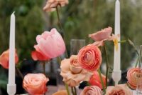 a cluster wedding centerpiece of coral, pink and peachy blooms, citrus and candles in candlesticks is lovely