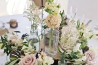 a cluster wedding centerpiece of wood slices, white and pastel blooms, greenery, candles and a table number