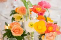 a colorful cluster wedding centerpiece of white, yellow and pink and red poppies, some pink tulips and candles around