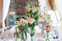 a delicate cluster wedding centerpiece of sheer bud vases and bottles, pink and white blooms and candles