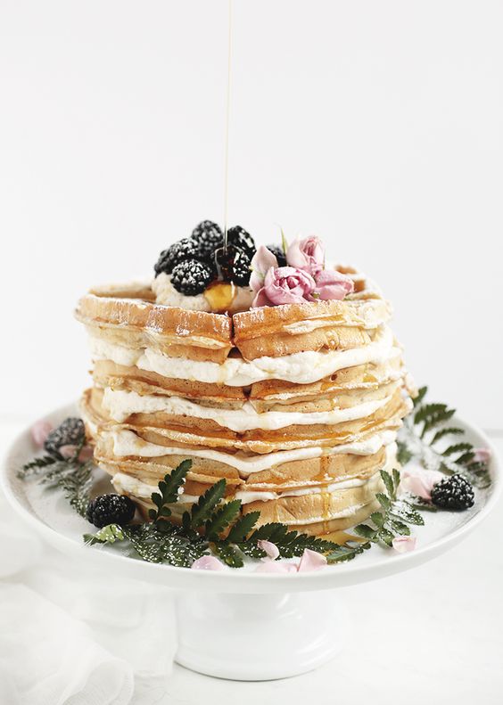 a delicious small waffle wedding cake with cream, fresh blackberries and pink blooms on top is amazing