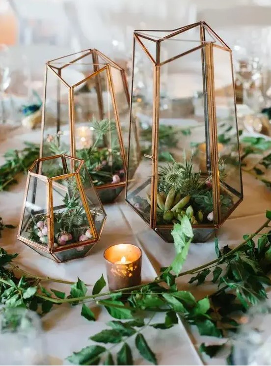 a modern cluster terrarium wedding centerpiece with thistles, succulents and rocks, with greenery and candles around is cool