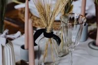 a modern cluster wedding centerpiece of colorful bunny tails, wheat and blush candles is ideal for a modern rustic wedding