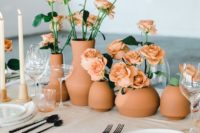 a modern cluster wedding centerpiece of terracotta vases and peachy roses looks bold and chic