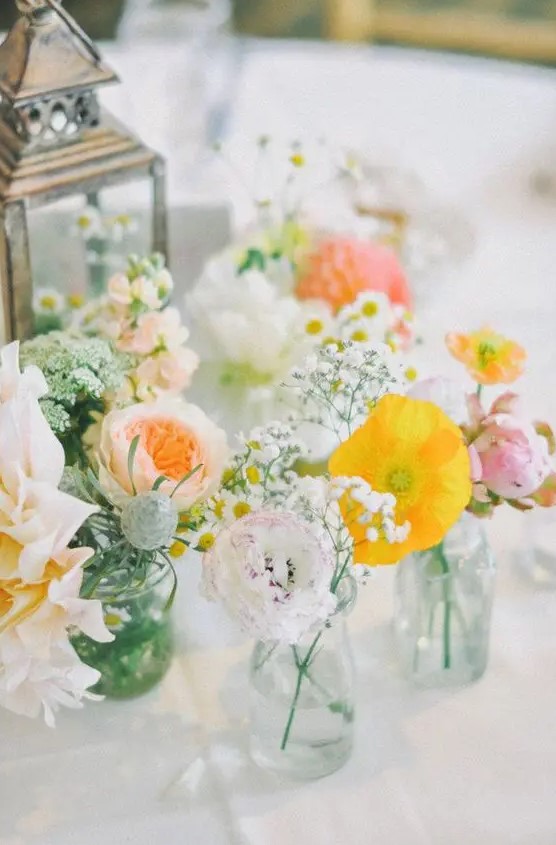 a pastel cluster wedding centerpiece of yellow poppies, blush and white dahlias, peony roses and baby's breath is chic