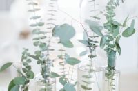 a pretty and simple cluster wedding centerpiece of bottles and with fresh eucalyptus is a great solution for a modern wedding