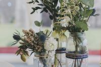 a rustic cluster wedding centerpiece of a wood slice, jars, neutral and blush blooms, greenery and thistles is wow