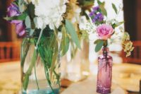 a rustic cluster wedding centerpiece of a wood slice, some jars and colorful and white blooms looks cool