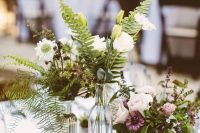 a rustic cluster wedding centerpiece of white, mauve and pink blooms, fern and greenery and some succulents
