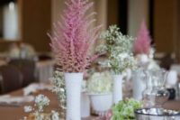a rustic cluter wedding centerpiece of white vases, white, pink and green blooms and candles