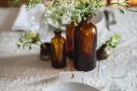 a simple cluster wedding centerpiece of apothecary bottles and greenery plus some simple blooms is a great idea for an organic wedding