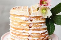 a simple waffle wedding cake with whipped creamy and a white and pink bloom with leaves on top is delicious