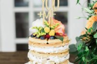 a small and delicious wedding cake with blueberries and raspberries, with pastel blooms and a cute and romantic topper