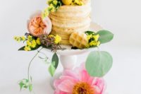 a small waffle wedding cake with yellow and pink blooms and greenery for a bright summer wedding