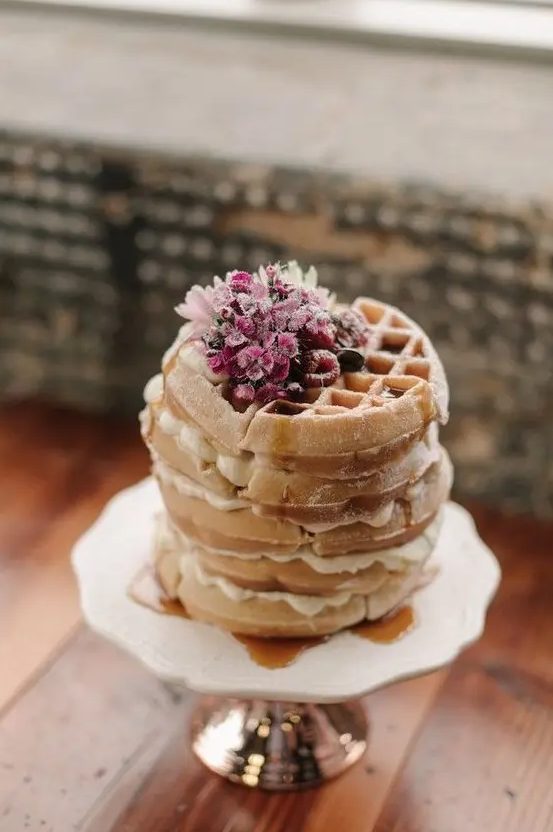a small yet lovely waffle wedding cake with cream and some raspberries and pink blooms on top is amazing