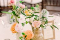 a stylish cluster wedding centerpiece with neutral and sheer vases, blush, pink, peachy blooms and greenery