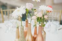 a very simple cluster wedding centerpiece of gold and copper bottles, white and pink flowers and greenery