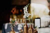 an elegant cluster wedding centerpiece of gold vases and bottles, neutral and pastel blooms is a chic and modern idea