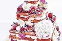 an oversized waffle wedding cake with various types of berries, white and pink blooms and some meringues
