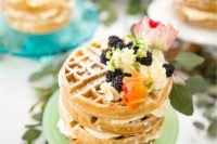several mini Belgian waffle cakes with whipped cream, blackberries and pink blooms on top