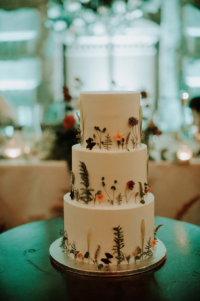 The white wedding cake was decorated with dried flowers and greenery