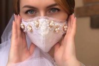 18 a white lace embellished face mask with pearls is a stylish glam option to go for, it will perfectly accent a bridal look