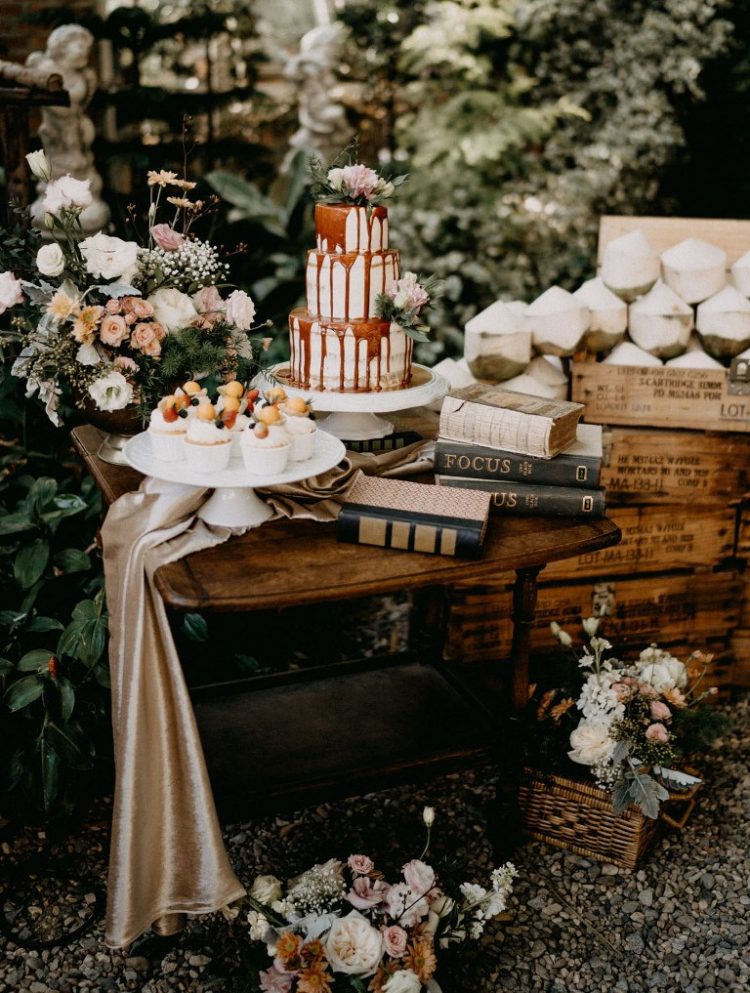 The wedding dessert table was done with pastel and white blooms, there were delicious cupcakes and a beautiful naked cake with caramel drip served