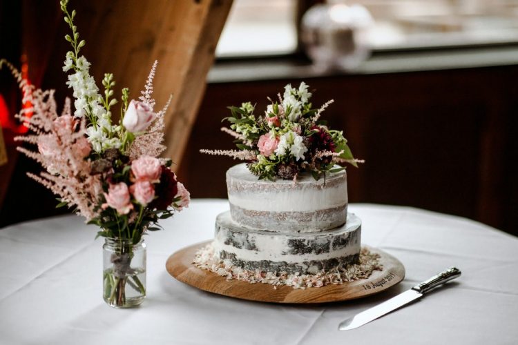 The wedding cake was a naked one, with greenery, burgundy and blush blooms on top