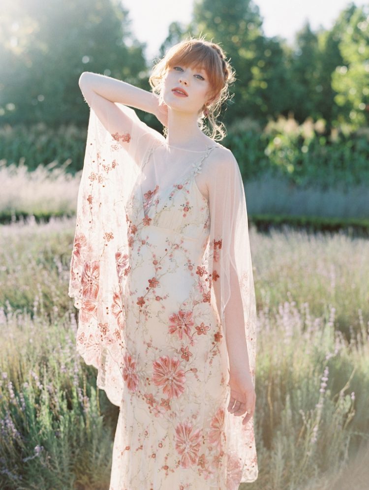 a delicate wedding dress in neutral shades with pink floral embroidery all over the dress and with a neutral underdress
