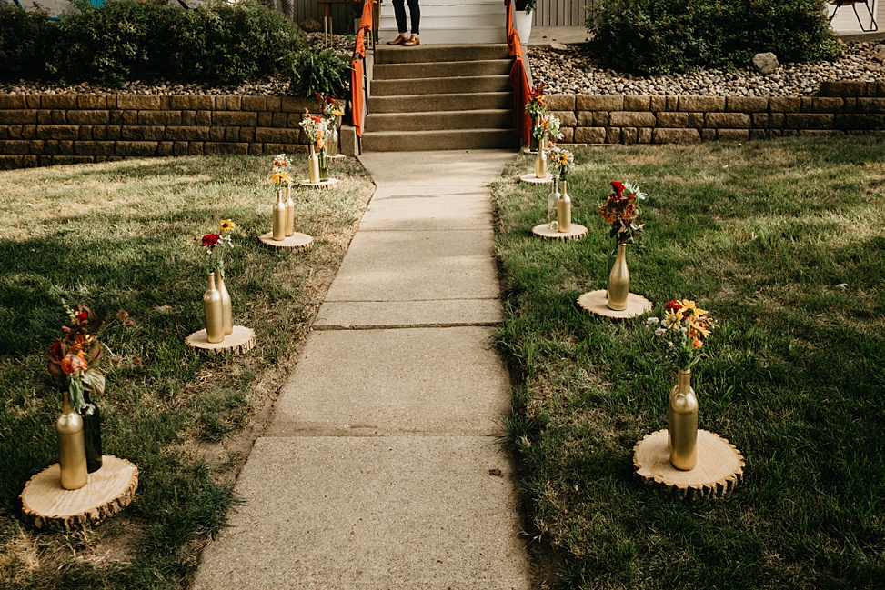 The ceremony took place on the couple's front porch, the path was lined with blooms in gold bottles