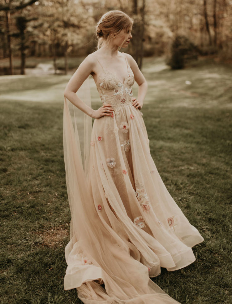 a beautiful nude wedding dress with floral appliques, a gauzy skirt, an open back and a capelet