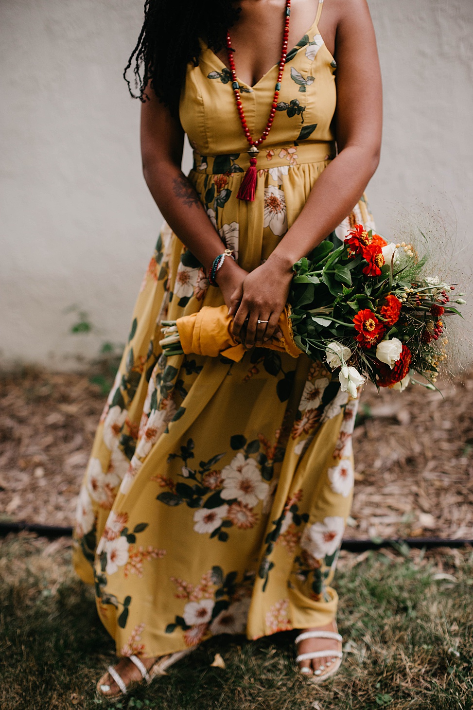 The bride was wearing a yellow floral A line maxi dress, a colorful veil and a necklace