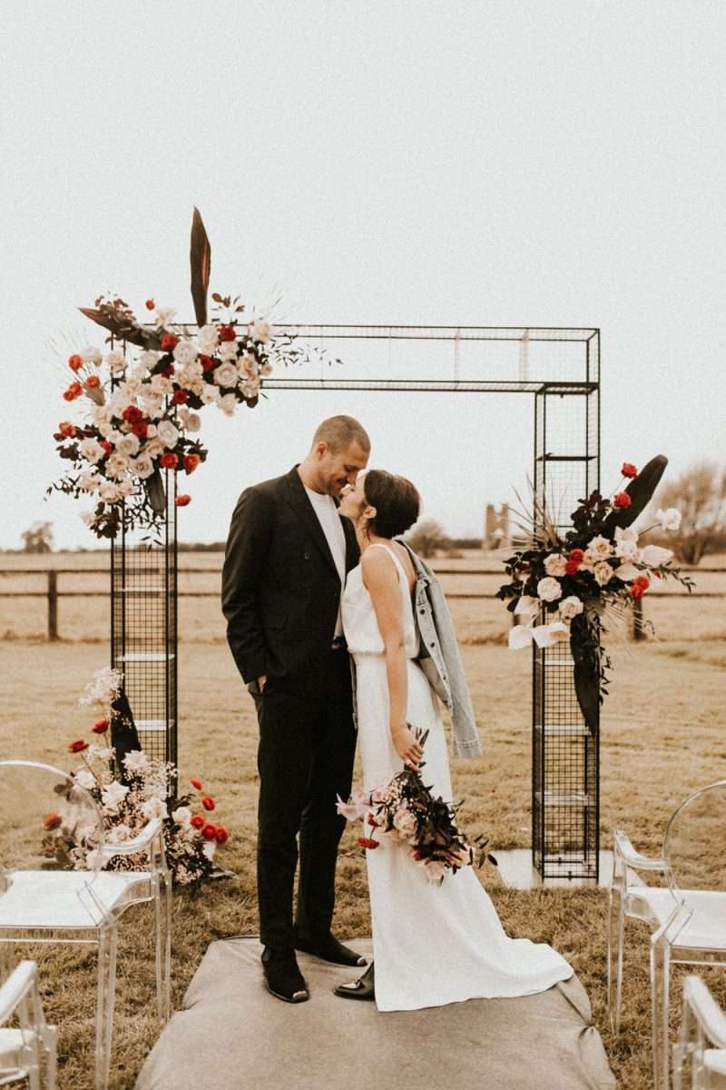 The metal wedding arch was decorated with blush and red blooms and dark leaves