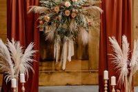 03 The wedding arch was done with burgundy curtains, candles, pampas grass and a lush floral arrangement with bright blooms and greenery