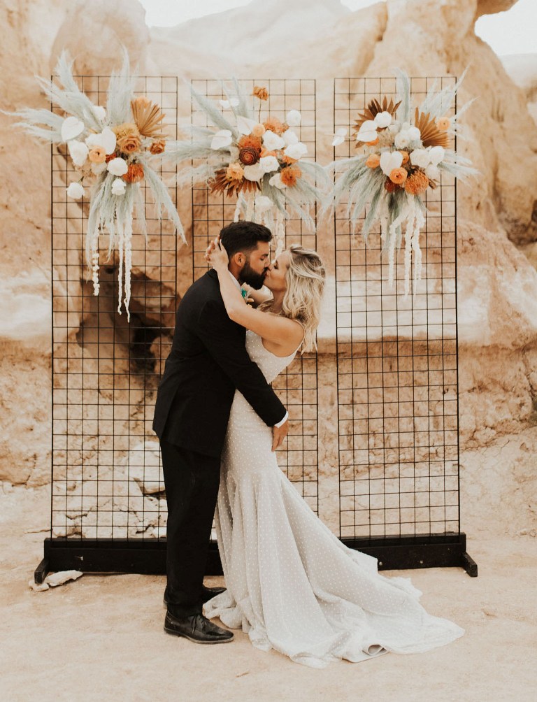The wedding backdrop was a grid with rust colored florals and green pampas grass