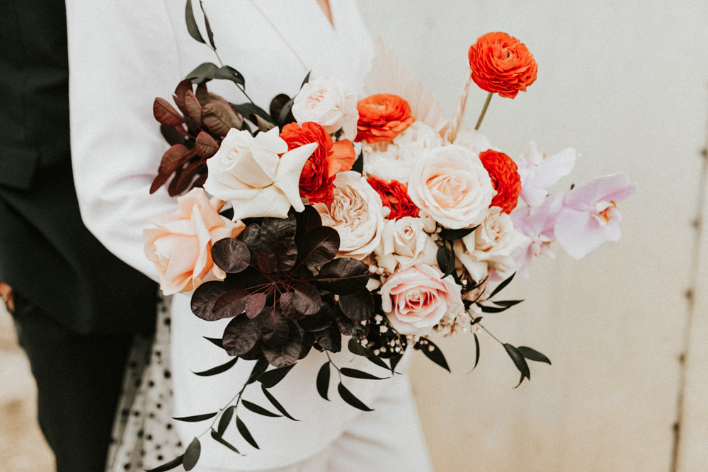 The wedding bouquet was composed of pink roses, red ranunculus, dark foliage