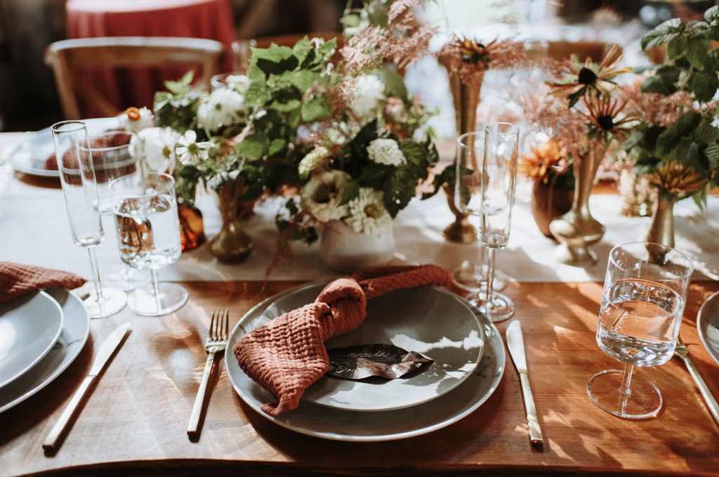The wedding tablescape was done with rust napkins, neutral and blush blooms and greenery