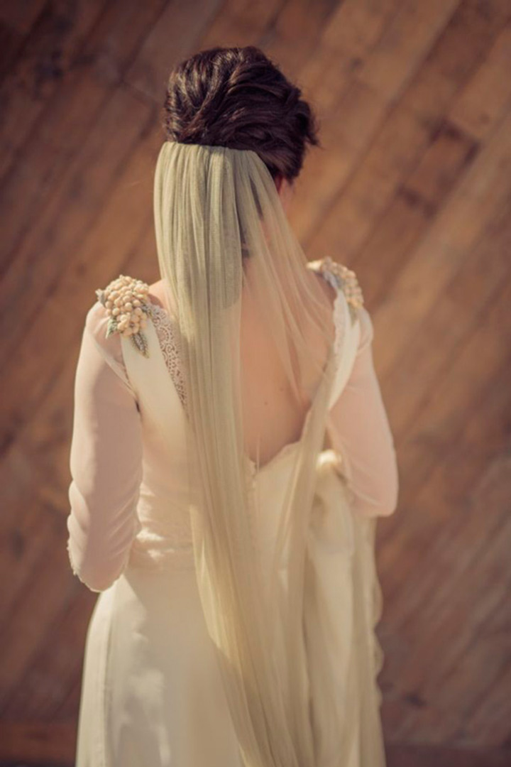 a romantic A line wedding dress with a cutout back, floral detailing on the shoulders and a light green veil