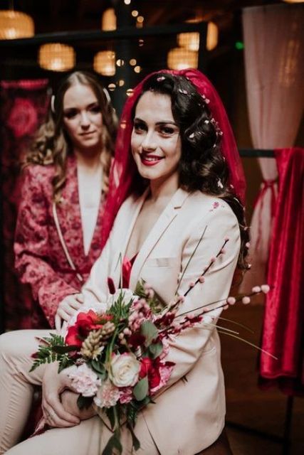a blush pantsuit, a deep red top and a matching veil and a lip for an ultimately gorgeous bridal look