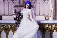 18 a gorgeous lace princess-style wedding gown with illusion sleeves and a neckline, a tain, purple hair and a dramatic bouquet