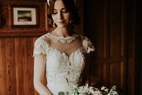 23 a romantic lace sheath wedding dress with an illusion neckline, cap sleeves and a sheer part in the skirt plus a statement headpiece