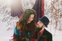 a printed red shirt, a printed black tie, a black suit and a navy hat with a bright feather for a winter woodland wedding