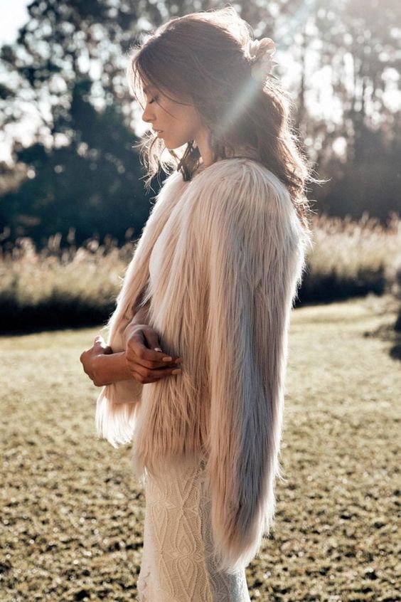 a blush fuzzy fur coat over a lace wedding dress to add a bit of edge to a romantic and glam bridal look
