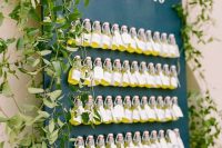 03 a black wall decorated with greenery and with Limonecello bottles as drinks or favors